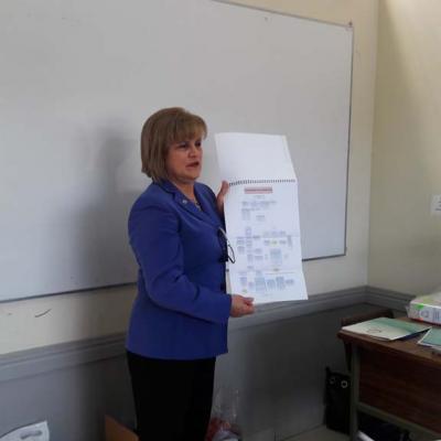 mujer de pie explicando  un documento que tiene en sus manos 