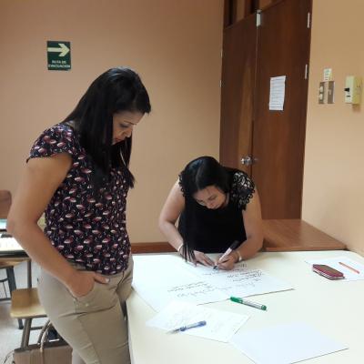 dos mujeres  escribiendo en una cartulina blanca