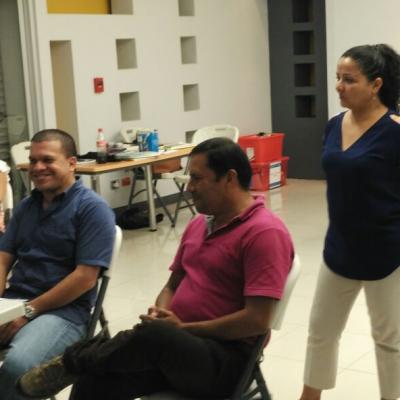 personas sentadas capacitándose y una mujer de pie