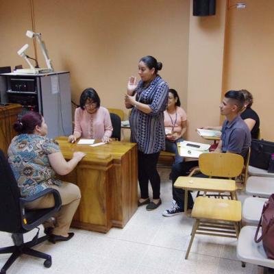 mujer explica de pie y alrededor personas sentadas la escuchan