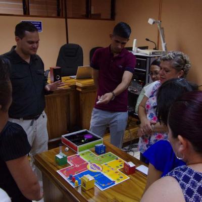 personas de pie, observando juego de mesa