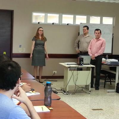 una mujer y dos hombres exponiendo de pie un tema