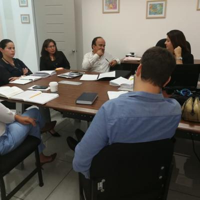 Personas reunidas en mesa de trabajo conversando