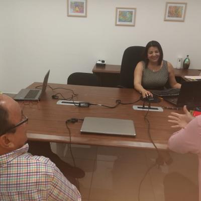 Mujer en su escritorio conversa con compañeros