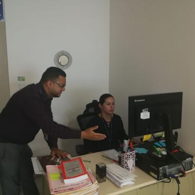Hombre señalando información a mujer sentada en escritorio