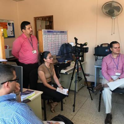 hombre de pie y mujer y hombre sentados con una cámara de grabar
